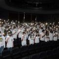 Estudantes com jaleco branco erguem vela #paratodosverem