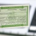 mão segura título de eleitor com urna eletrônica ao fundo. #paratodosverem 