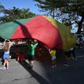 crianças brincando com lona colorida #paratodosverem