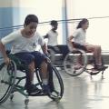 Crianças na cadeira de rodas correm em ginásio