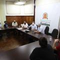 Pessoas conversam sentadas em uma mesa em forma de U #paratodosverem