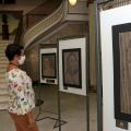 Mulher observa quadros expostos. #Paratodosverem