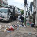 caminhão está parado em rua. Há muito lixo no chão em torno do imóvel. #paratodosverem