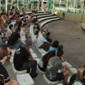 Público sentado na concha acústica assiste palestrante mulher. #pratodosverem
