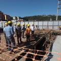 várias pessoas usando capacete estão olhando andamento de obra. #paratodosverem