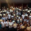 alunos estão na plateia de teatro ostentando certificados. #paratodosverem