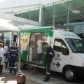 van odontológica está parada em frente a terminal. diante dela há uma tenda com pessoas usando avental branco. Trabalhadores portuários estão uniformizados. #paratodosverem