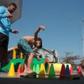 menino brinca de se equilibrar entre cones. O pai observa.#paratodosverem