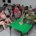 professor fala a alunas com flores em mesa na frente #paratodosverem