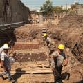 homens estão trabalhando em terreno. eles mexem em estruturas de ferro. #paratodosverem