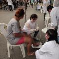 Voluntários fazem curativo no pé de uma mulher. #paratodosverem