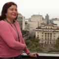 monica posa para foto em uma janela, com o palácio josé bonifácio ao fundo. #paratodosverem