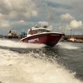 lancha dos bombeiros no mar em movimento com armazéns portuários ao fundo. #paratodosverem