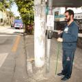 homem está ao lado de botoeira em poste pronto para fazer a travessia de pedestres. #paratodosverem