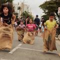 crianças brincam de pula-saco na avenida da praia. #paratodosverem