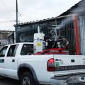 carro com equipamento de dispersão de líquido percorre rua. #paratodosverem