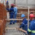 operários estão trabalhando entre ferragens, todos com equipamentos de segurança. #paratodosverem