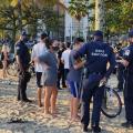 guardas municipais estão em torno de pessoas na faixa de areia. #paratodosverem