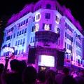Fachada do hotel iluminada com palco à frente. #paratodosverem