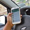 Mão está com celular ao volante #pracegover 