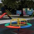 parque infantil com gira-gira em primeiro plano, balancês à direita, escorredor à esquerda e um castelinho ao fundo. #paratodosverem 