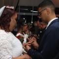 casais enfileirados colocam suas alianças. Mulheres estão vestidas de noiva. #paratodosverem 