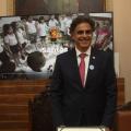 o ministro está em pé diante de uma placa de homenagem sobre uma mesa.  #paratodosverem