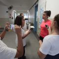 Alunos filmam, fotogravam e entrevistam uma mulher no corredor de escola. #Pracegover