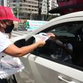 mulher distribui panfleto em carro #paratodosverem