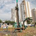homens estão trabalhando em canteiro de obras em meio a máquinas de fundação. #paratodosverem