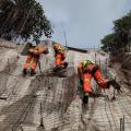 profissionais escalando encosta de morro durante obra #paratodosverem