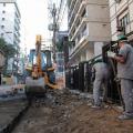 trator na rua removendo paralelepípedos e homens trabalhando, #paratodosverem