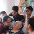 filhos e netos olham com carinho para matriarca sentada #paratodosverem