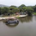 vista aérea da lagoa da saudade, com palco flutuante na água, vegetação e área de lazer ao fundo. #paratodosverem