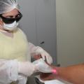 Enfermeira realiza aplicação de laser em pé de paciente. #paratodosverem 