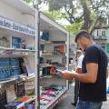 Homem escolhe livro na biblioteca móvel na Praça Mauá. #paratodosverem