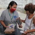 mulher usando máscara entrega folheto e saquinho de papel