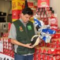 fiscal segura e olha para ovo de páscoa. Atrás dele há várias caixas de chocolate. #paratodosverem