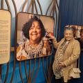 mulheres à frente de paineis de fotos sobre pesca. #paratodosverem