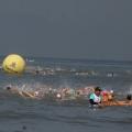atletas nadando no mar. Ao fundo uma boia grande onde se lê 'Santos'. #paratodosverem