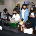 Crianças mostram brinquedos para outras crianças sentadas #paratodosverem