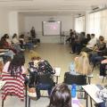 sala de aula com várias pessoas sentadas em roda assistindo a uma palestra. #paratodosverem