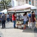 pessoas na praça com várias tendas #paratodosverem