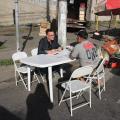 Em uma mesa na rua, homem recebe atendimento #paratodosverem