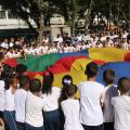 Crianças erguem tecido colorido em movimento conjunto. #paratodosverem