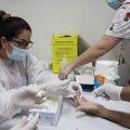 mulher retira gotinha de sangue de dedo de pessoa #paratodosverem