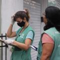 duas agentes uniformizadas estão paradas em porta de residência. #paratodosverem 