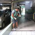 agente está em pé em garagem iluminando ralo com lanterna. #paratodosverem
