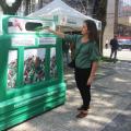 mulher coloca garrafa de vidro dentro de recipiente em praça. #paratodosverem