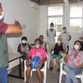 agente de saúde está em pé falando a mulheres que estão sentadas. #paratodosverem